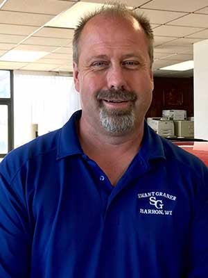 Man with a goatee wearing a blue polo shirt with SWANT GRABER BARRON, WI logo, smiling at the camera